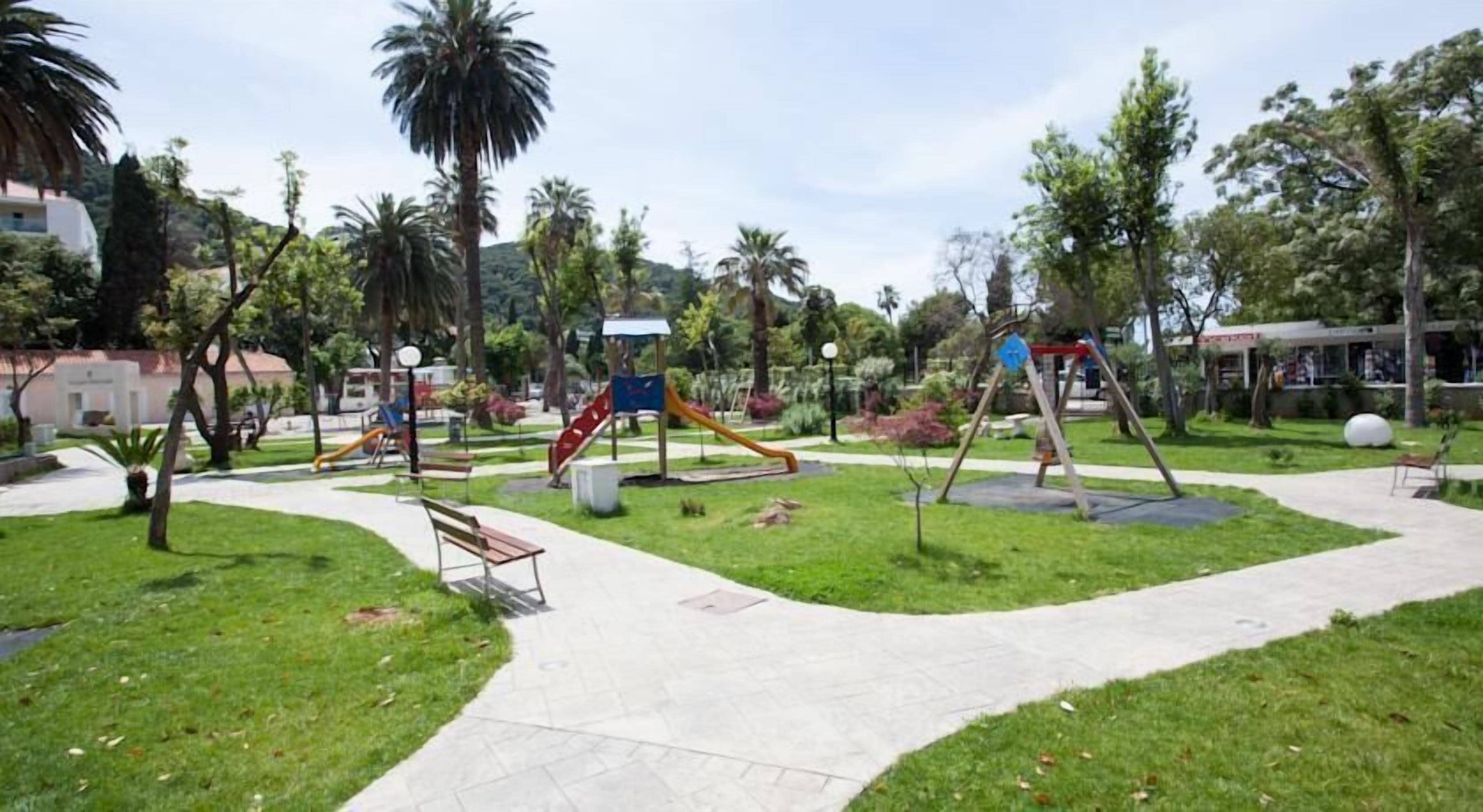A park with playground equipment, benches, and a walking path.