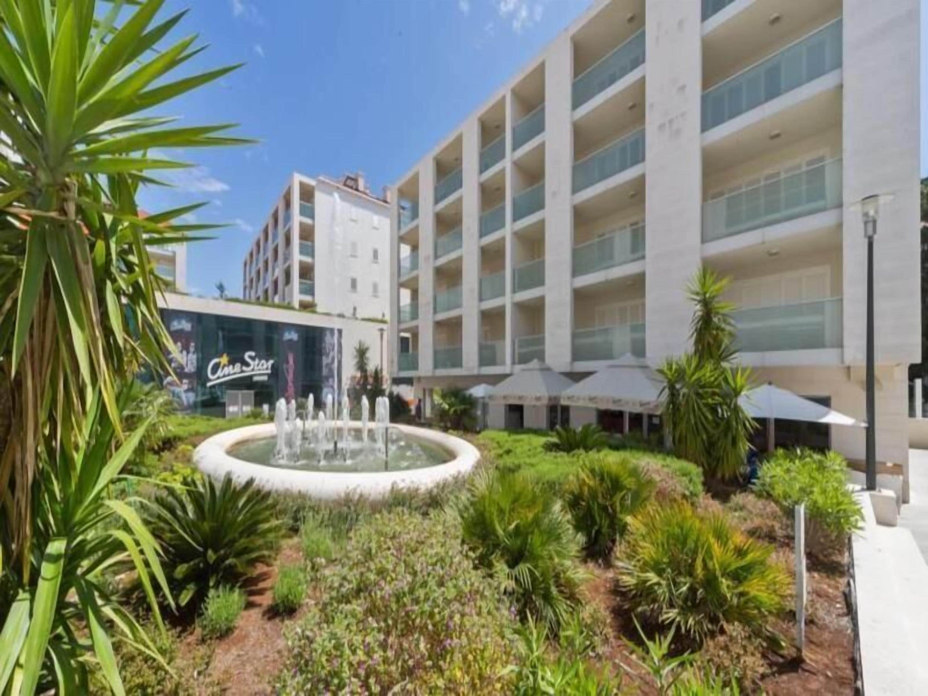 Un hotel moderno con un patio central, una fuente y un cine 'CineStar'.