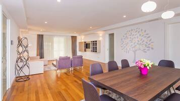 A modern dining area with a wooden table, purple chairs, and a pink vase of flowers.