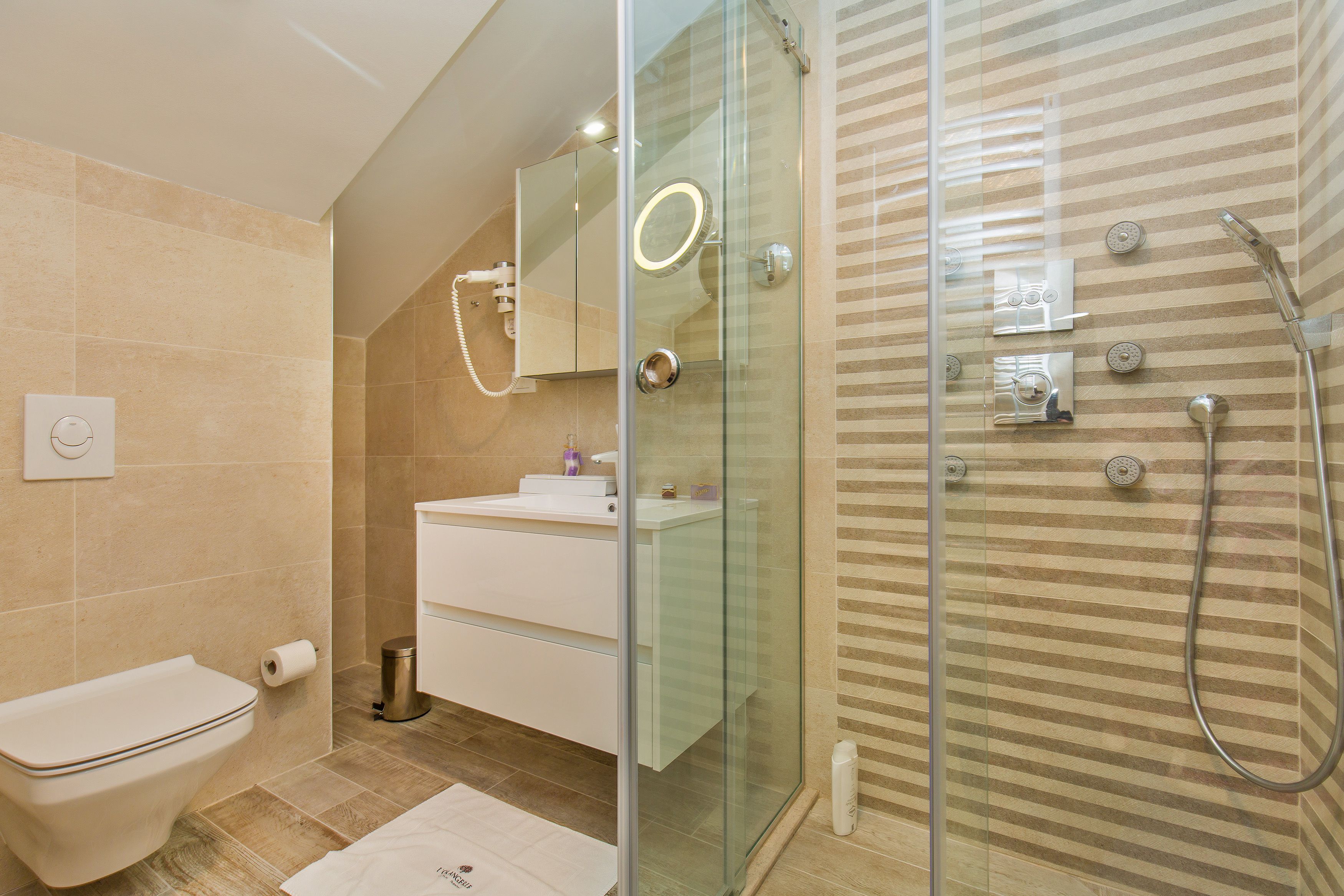 Un baño moderno con ducha de vidrio, un lavamanos blanco y un inodoro.