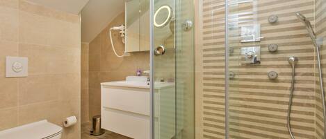 A modern bathroom with a glass-enclosed shower, a white sink, and a toilet.