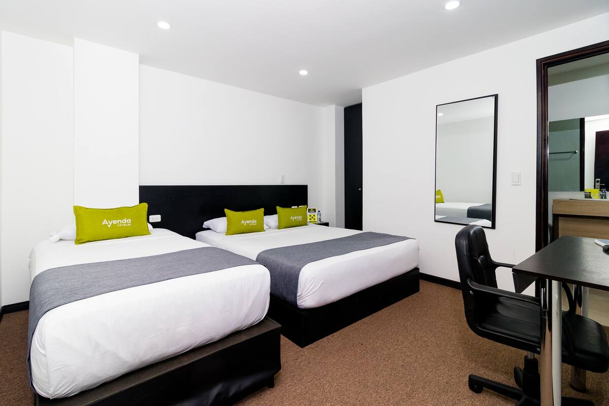Een hotelkamer met twee bedden, een bureau en een stoel.