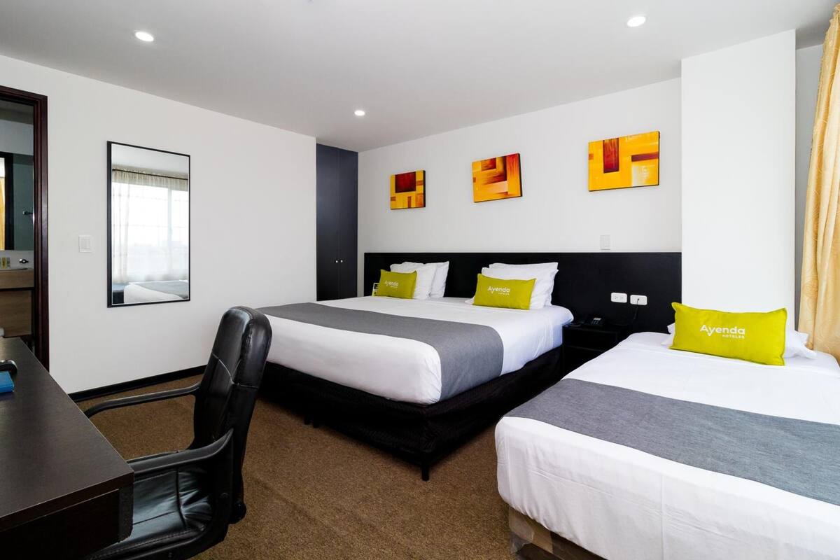 Een hotelkamer met twee bedden, een bureau en een stoel.