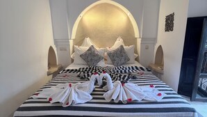 Una habitación de hotel con una cama grande, ropa de cama a rayas y toallas decorativas.