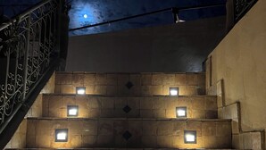 Una escalera con luces cuadradas iluminadas incrustadas en paredes de piedra, que conduce a un nivel superior.