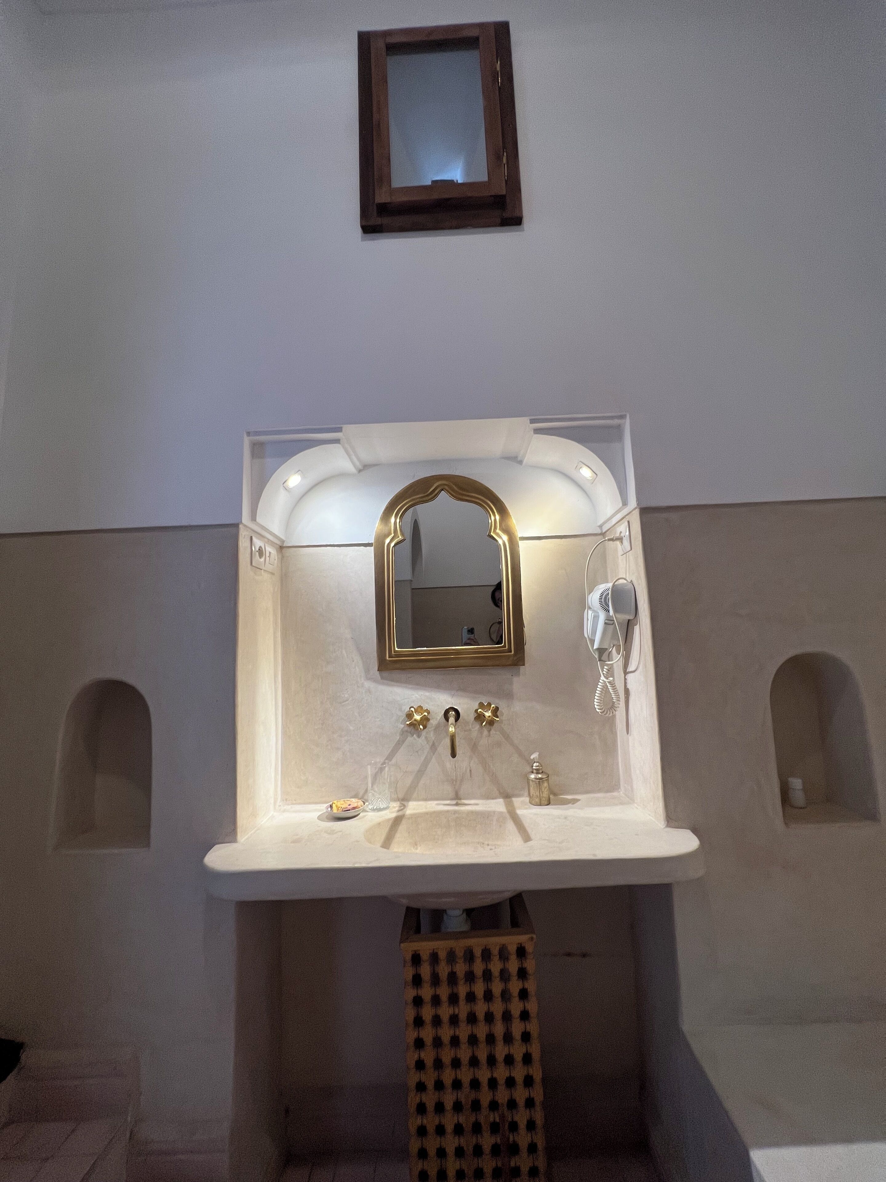 A bathroom with a sink, mirror, and a hairdryer.