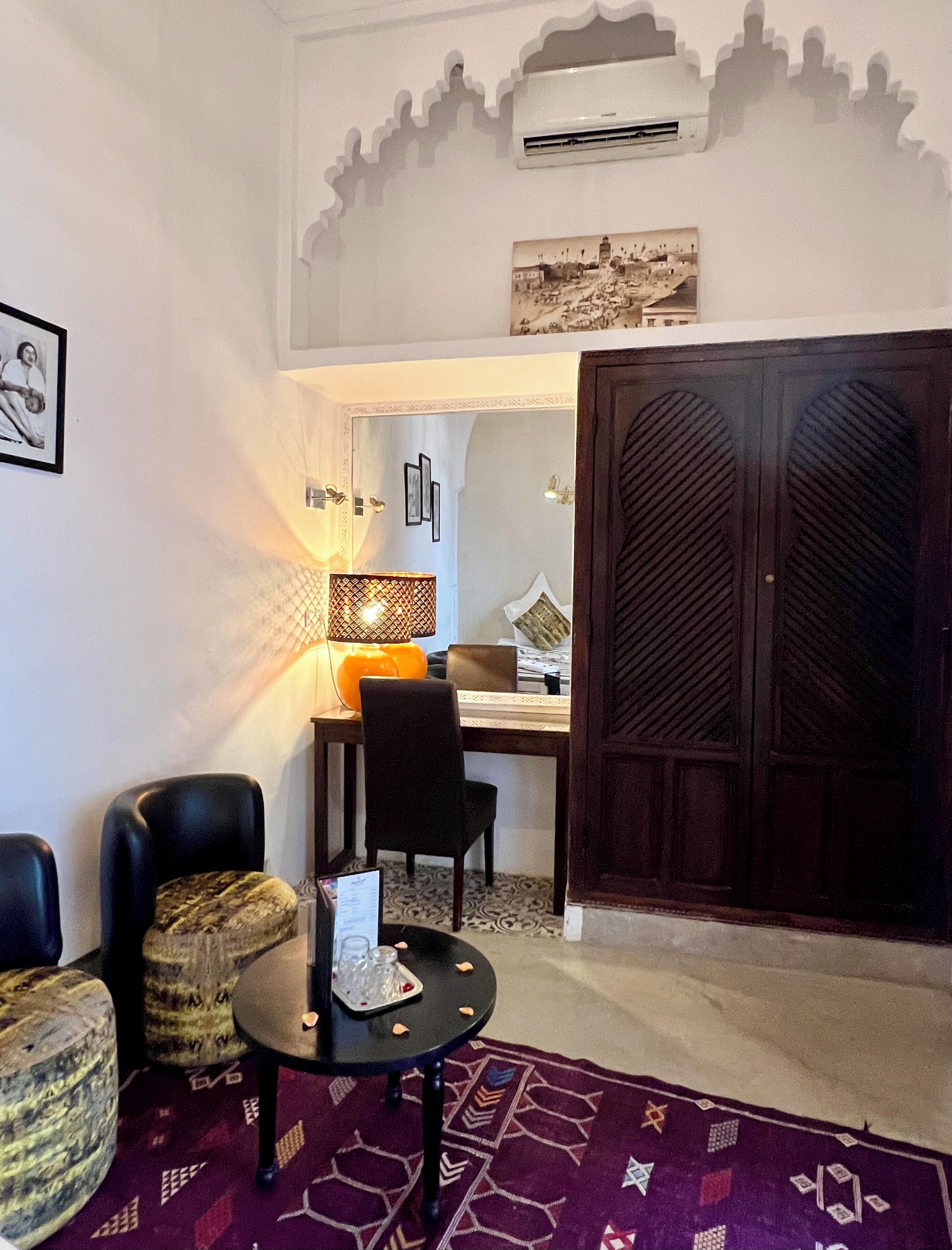 A room with a dining area, a sofa, a small table with a decorative item, and a patterned rug.