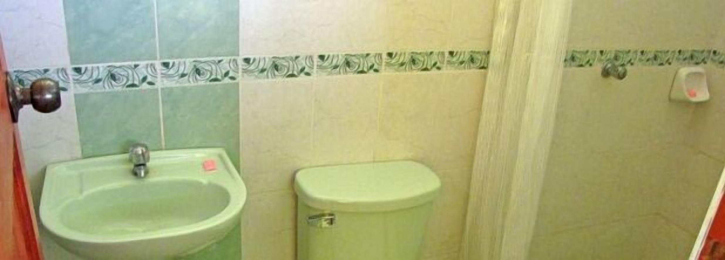 A bathroom with a sink and a toilet, both in a light color.