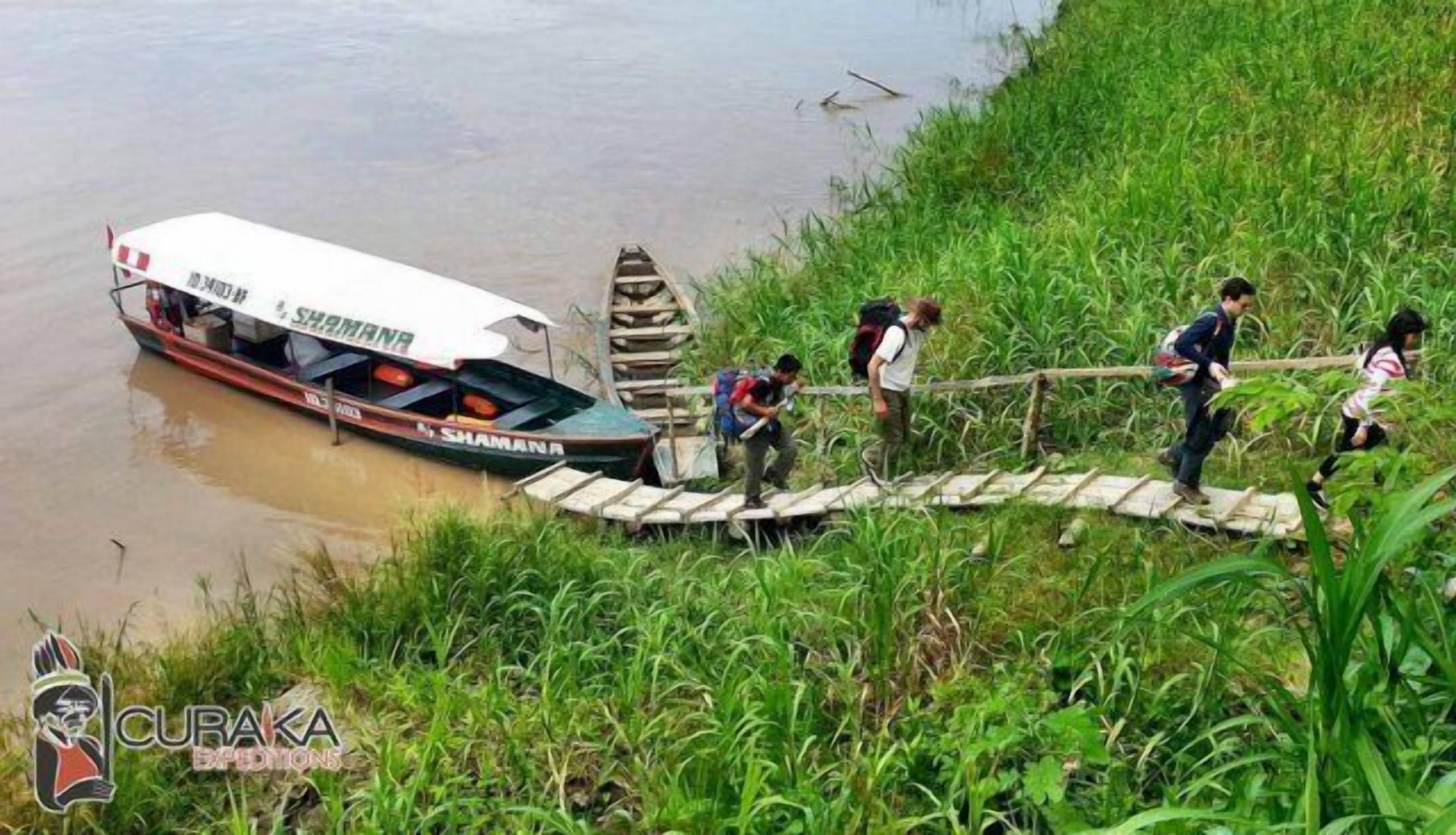 A boat stranded on a muddy bank with people attempting to pull it out.