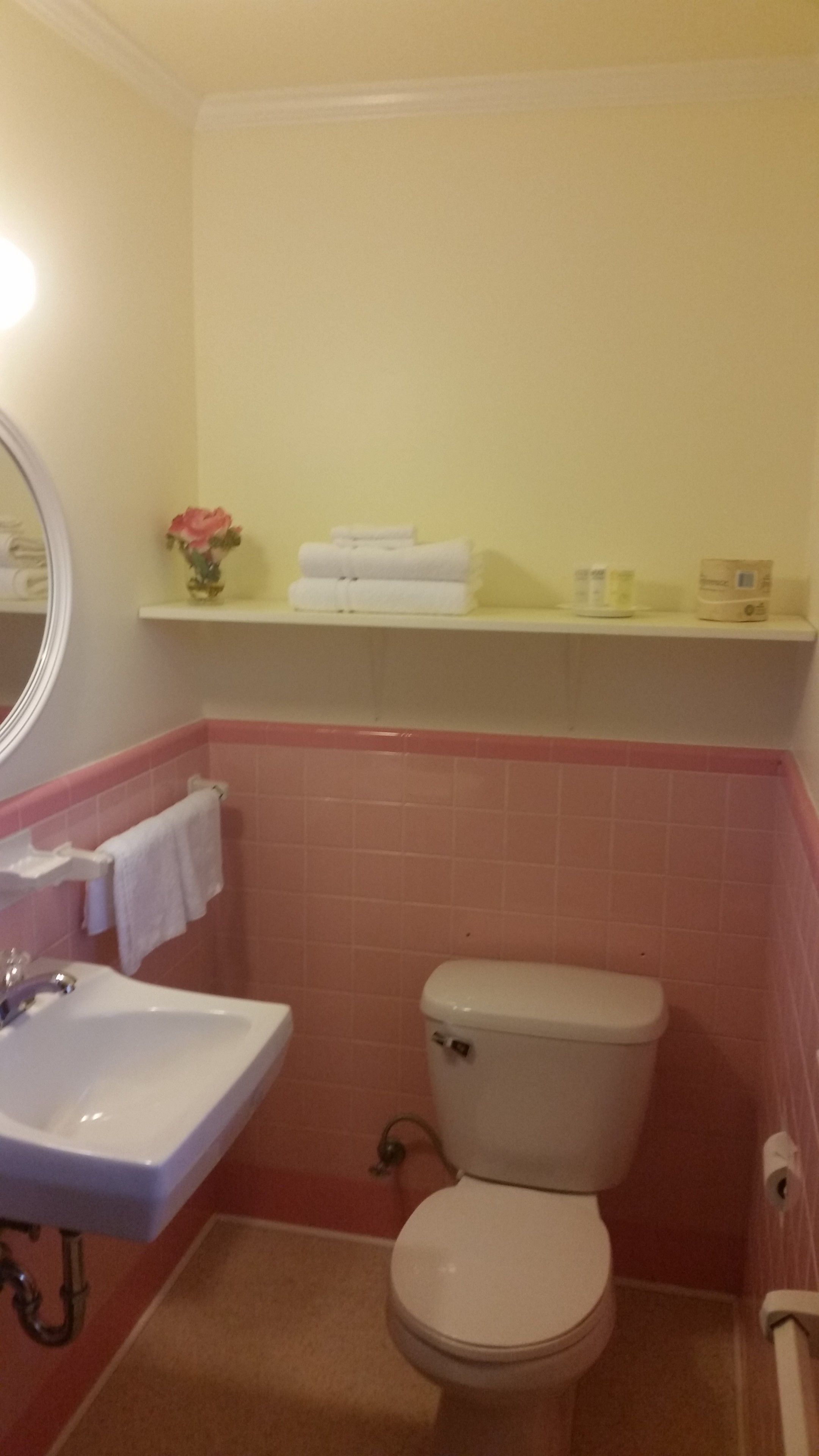 A bathroom with a sink, toilet, and a shelf above the toilet.