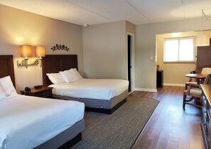 A hotel room with two beds, a desk, and a chair. There is a door leading to another room and a window with blinds. - Roosevelt Inn of Hyde Park (Hyde Park)