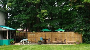 A backyard with a wooden fence, a patio table, chairs, and a sign that reads "Coffee Shop".