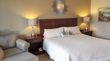Habitación de hotel con una cama grande, dos mesitas de noche con lámparas, un cabecero de madera y un espejo decorativo en la pared.