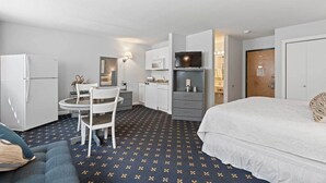 A compact hotel room with a bed, a small kitchenette, a dining area with a table and chairs, and a bathroom. - The Niantic Inn (Niantic)