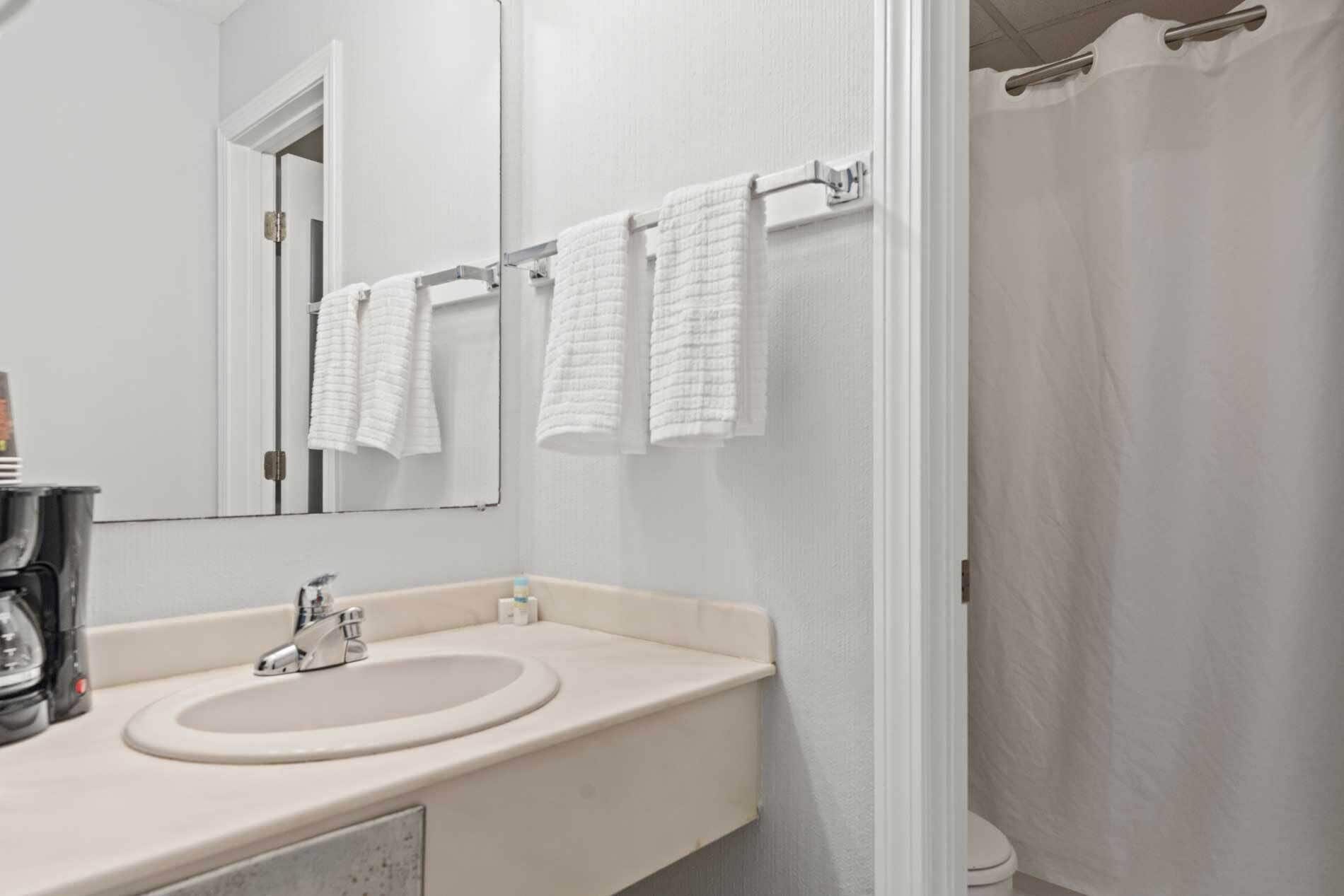 Une salle de bain équipée d’un lavabo, d’un miroir et d’un porte-serviettes.