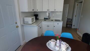 A dining area with a round table, chairs, and a tray with cups and a vase.