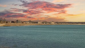 A waterfront view with a cityscape in the background during sunset.