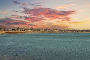 A waterfront view with a cityscape in the background during sunset.