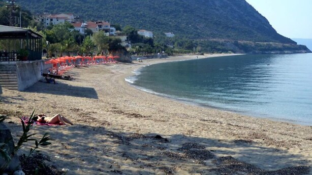 A beach with a mountain backdrop, umbrellas, and a few people. - Petros Studios (Kefalonia)