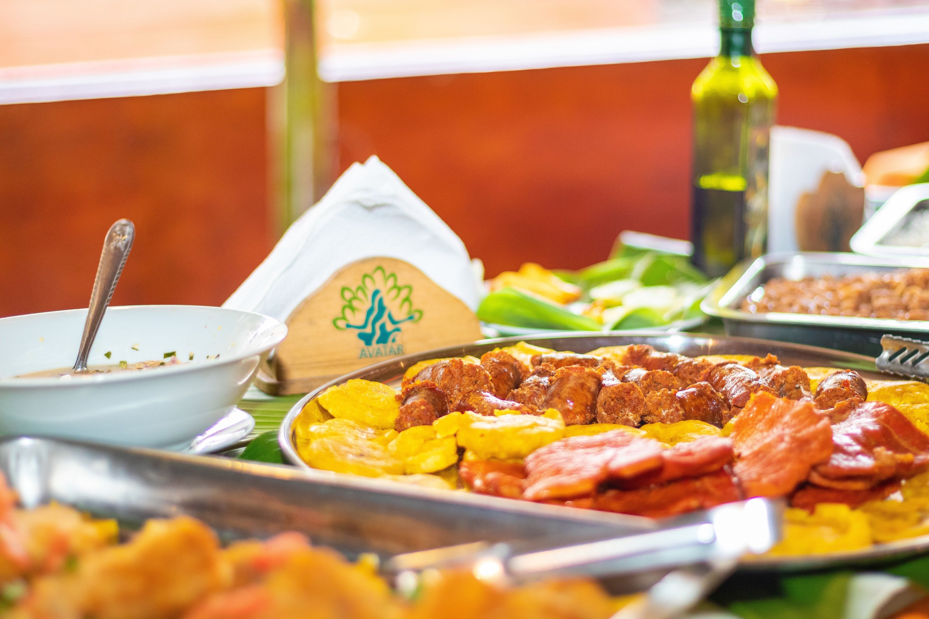 A buffet with various dishes, including meat and potatoes, and a bottle of olive oil.
