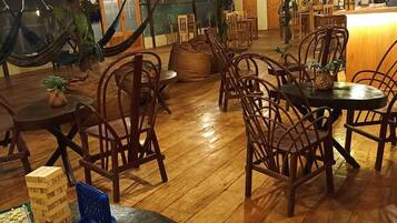 Amplio espacio interior con piso de madera, varias mesas y sillas de madera, y una variedad de juegos de mesa.
