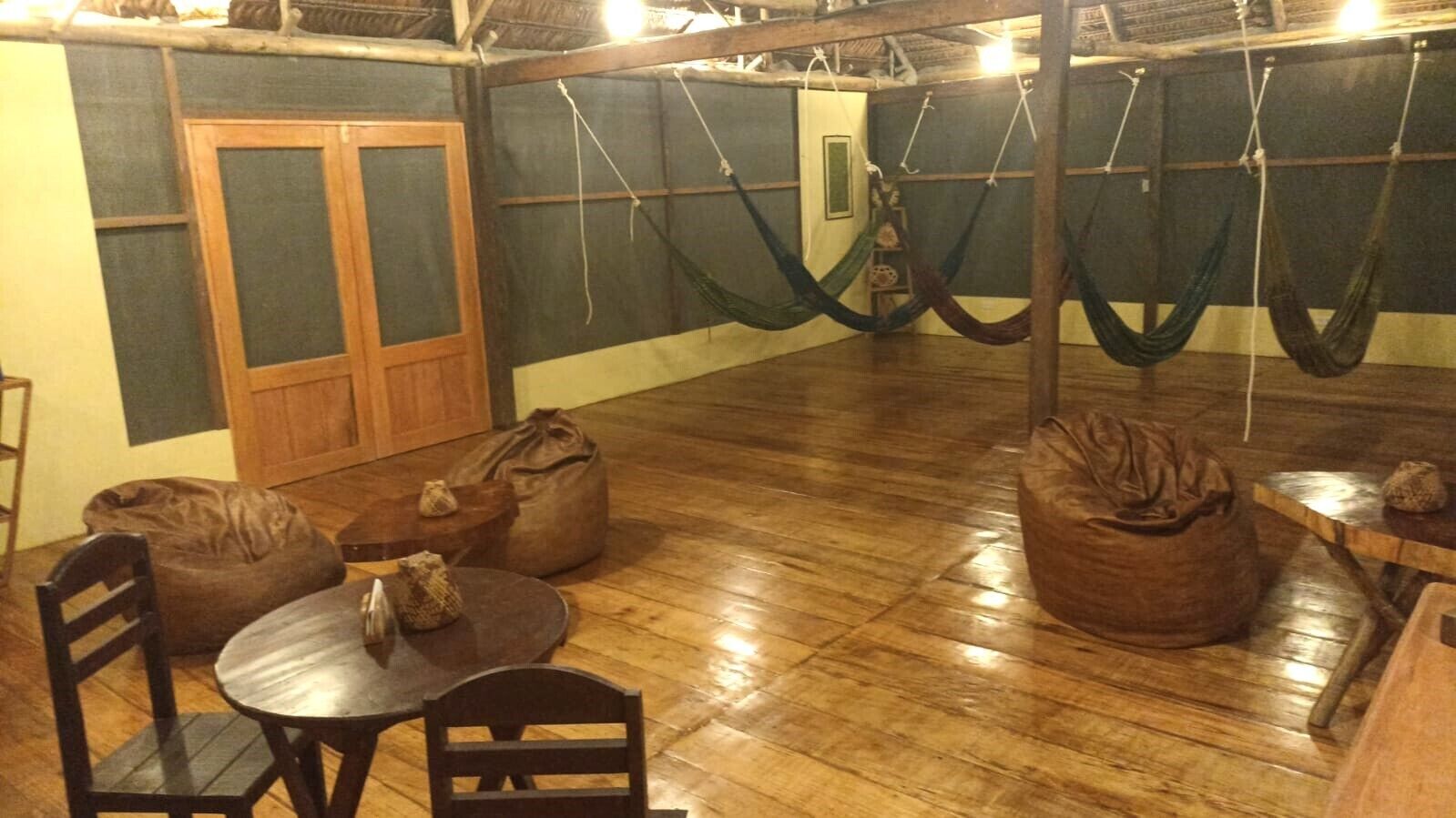 A room with wooden flooring, a round table with chairs, and several bean bags.