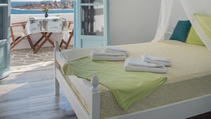 Un dormitorio con cama, ventilador de techo, mesita de noche, una silla y vista al mar.