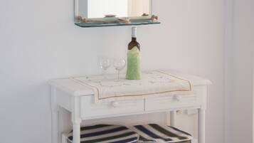 A white vanity with a mirror, a bottle, and two glasses.