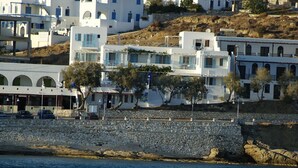 Un pueblo costero con edificios blancos, un muro de piedra y vista al mar.