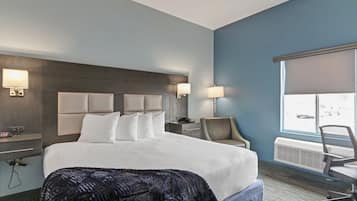 A hotel room with a large bed, bedside lamps, a chair, a desk, and a window with a view.