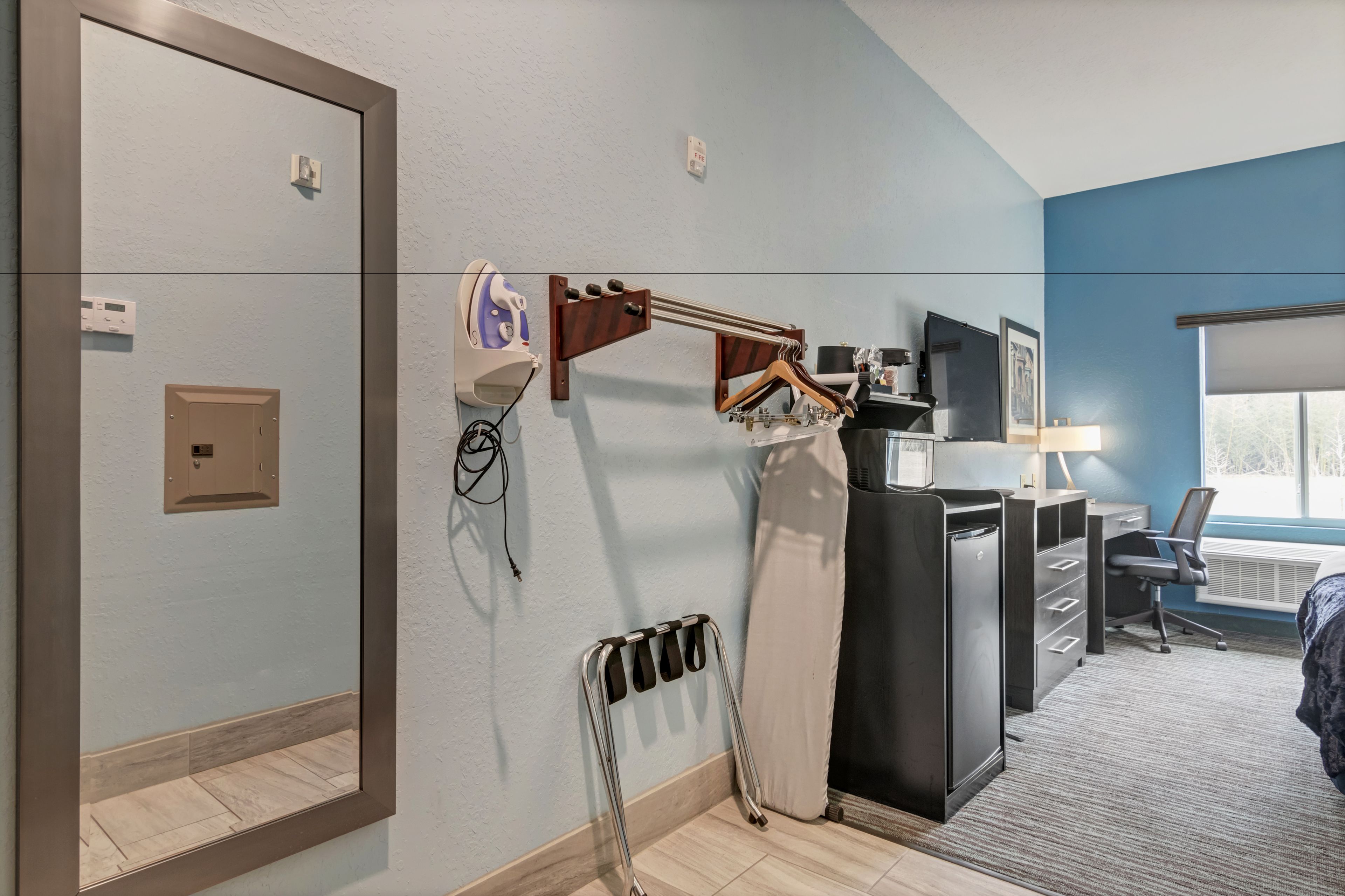 Hotelkamer met een grote spiegel, een bureau met een computer, een stoel, een radiator en een raam met uitzicht.