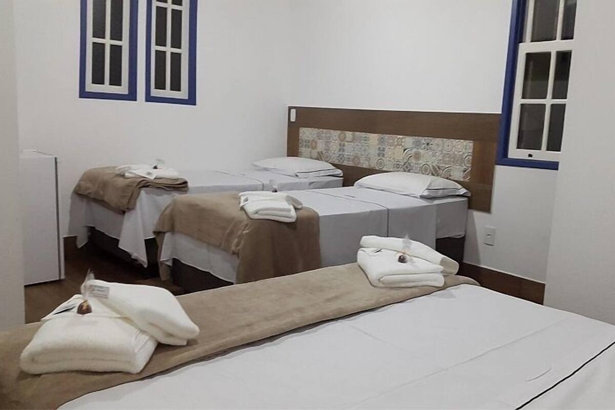 Ein Hotelzimmer mit zwei Einzelbetten, einem großen Bett und einem kleinen Tisch mit Handtüchern.