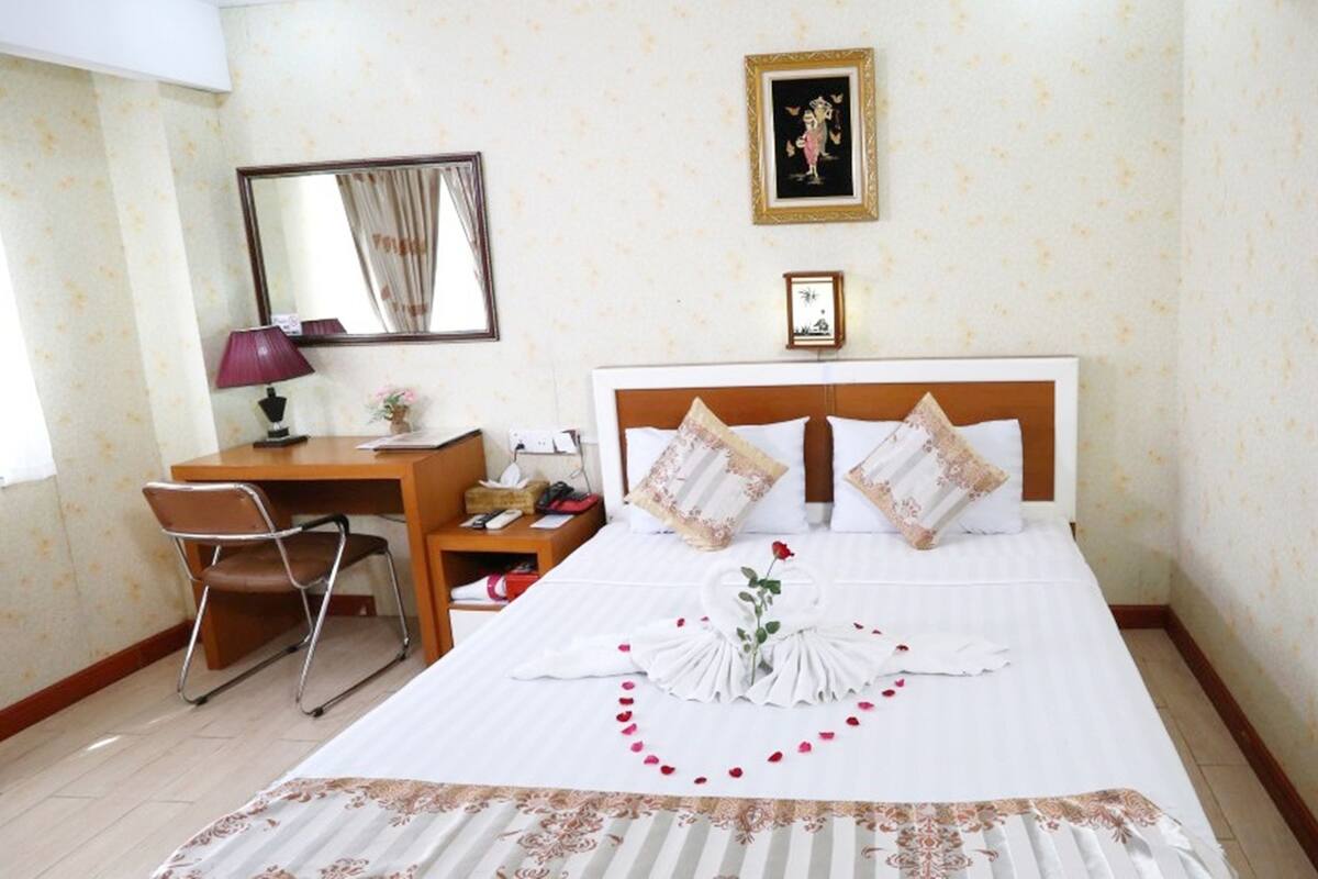 Une chambre d’hôtel bien rangée, avec un lit, un bureau et une chaise.