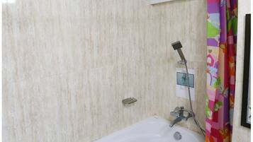Un baño con una bañera blanca, un cabezal de ducha y una cortina colorida.