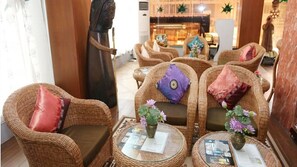 A lobby with wicker furniture, including chairs and a sofa, with cushions and a small table with a vase of flowers. - Hotel Kan Kaw (Yangon)