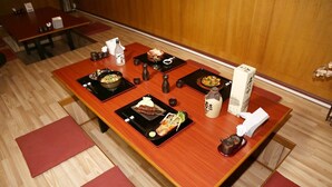 Una mesa tradicional japonesa con diversos platos, palillos y una botella de sake.