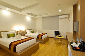 A hotel room with two beds, a small table, a chair, a TV, and a desk with a kettle and cups. - Serene Valley Hotel (Yangon)