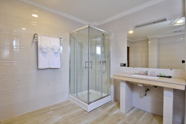 Un baño moderno con ducha de vidrio, un espejo grande y un mueble de tocador de madera.