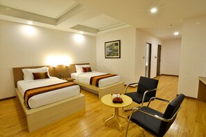 A hotel room with two beds, a small table, a chair, and a painting on the wall. - Serene Valley Hotel (Yangon)