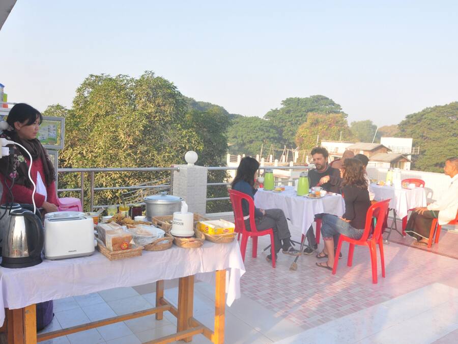 Zona de comedor en la azotea con mesas, sillas, alimentos y un hervidor.
