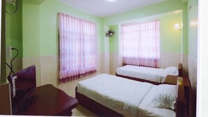 Una habitación con dos camas, un escritorio y un ventilador.