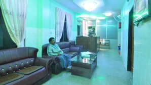 Una sala de estar con un sofá de cuero marrón, una mesa de centro de vidrio y una persona sentada en el sofá.