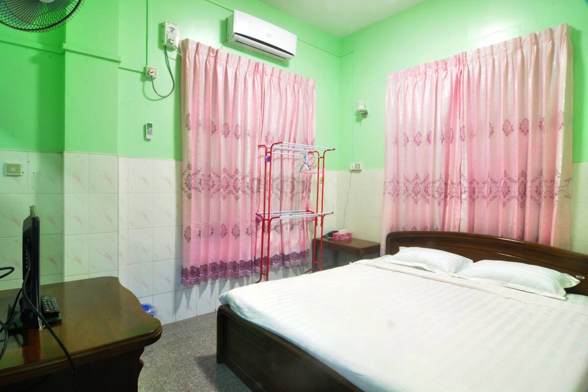Une chambre d’hôtel équipée d’un lit, d’une table de chevet, d’un téléviseur et d’un climatiseur fixé au mur.