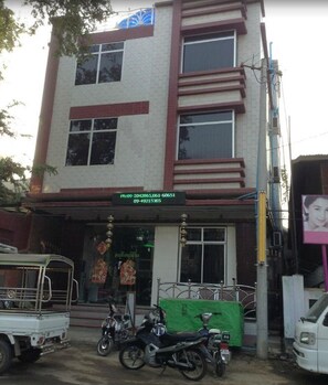 A multi-story building with a signboard displaying contact information. - Saw Nyein San Guest House (Nyaung-U)