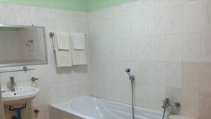 Un baño con una bañera blanca, un lavabo y un espejo. Hay dos toallas colgadas en la pared.