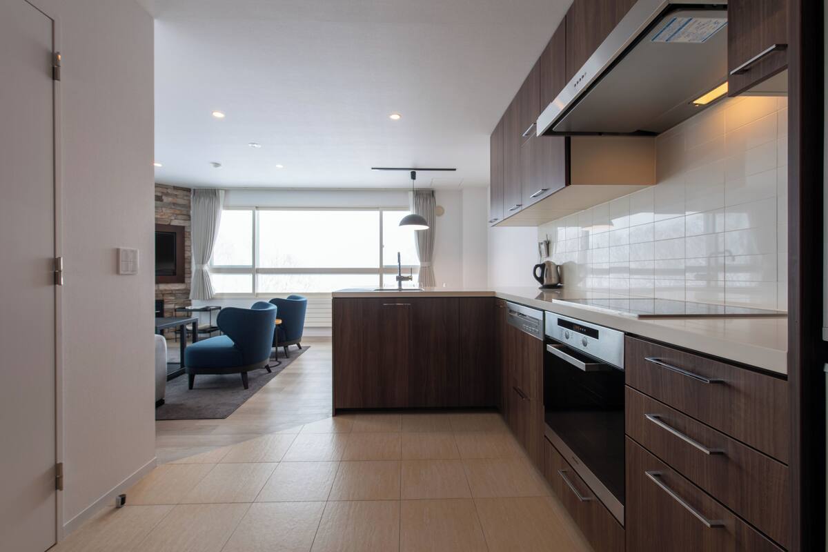 A modern kitchen with wooden cabinets, a white countertop, and a built-in dishwasher.