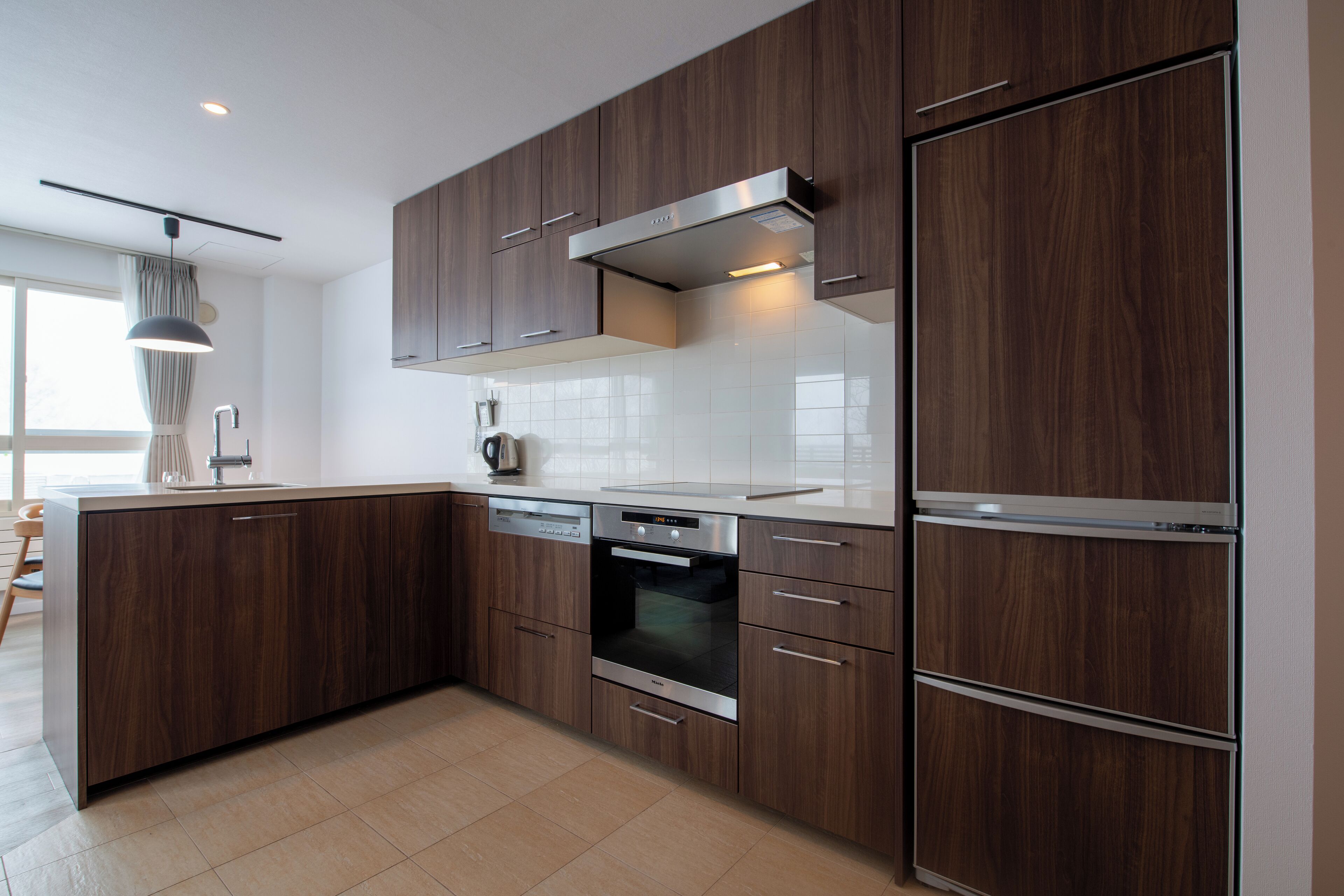 Een moderne keuken met donkere houten kastjes, roestvrijstalen apparatuur en een grote koelkast.