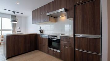 Een moderne keuken met donkere houten kastjes, roestvrijstalen apparatuur en een grote koelkast.