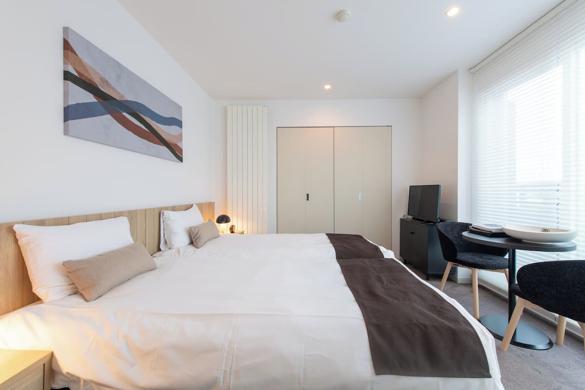 A modern hotel room with a large bed, a desk, and a television.