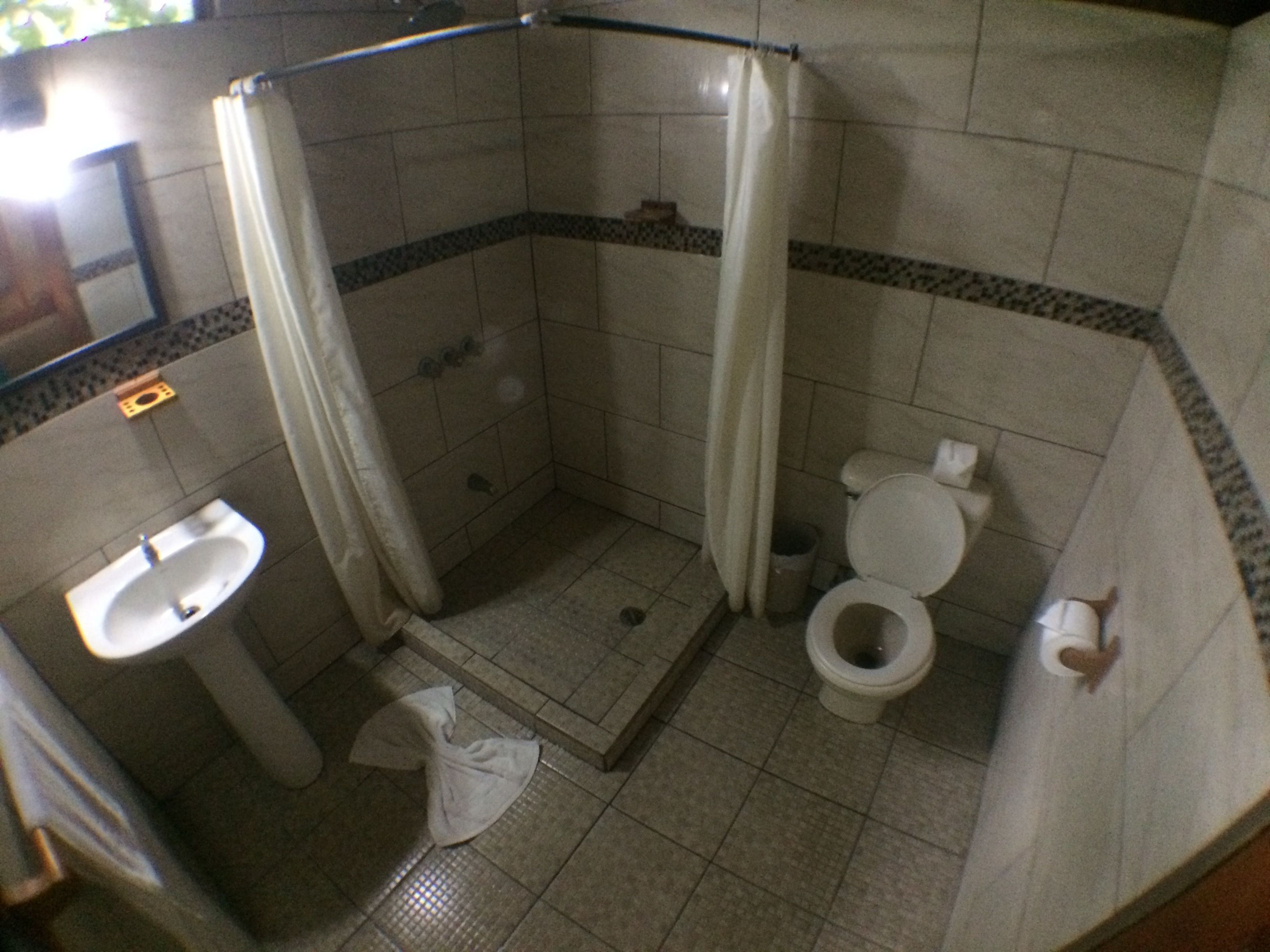 Un baño pequeño con ducha, inodoro y lavamanos.